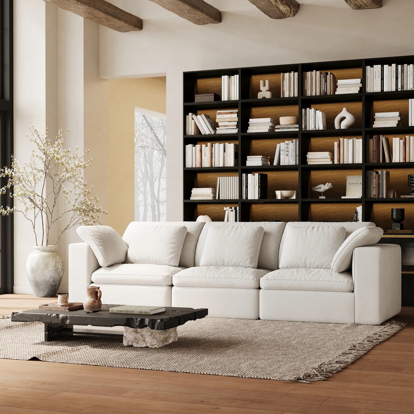 The quiet-style living room is furnished with a modular three-seater white sofa and a whole wall of modular black bookcases.