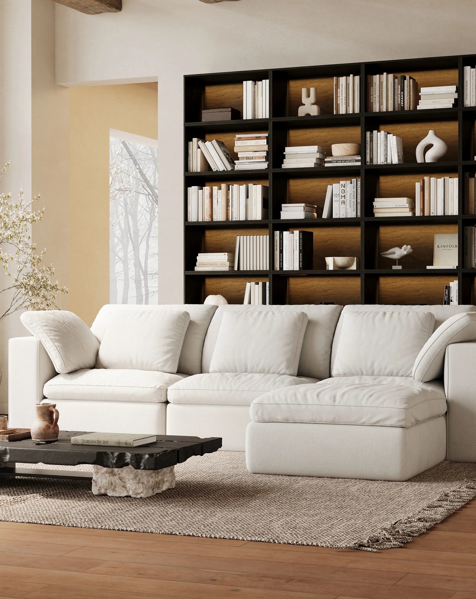 The quiet-style living room is furnished with a modular 4-seater white sofa and a whole wall of modular black bookcases.