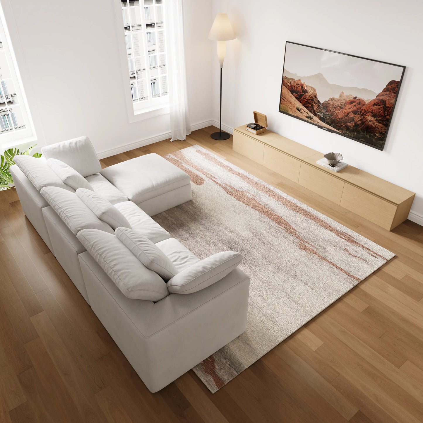 A small modern living room features a modular four-seater white L-shaped sofa and a modular wood-colored TV cabinet.
