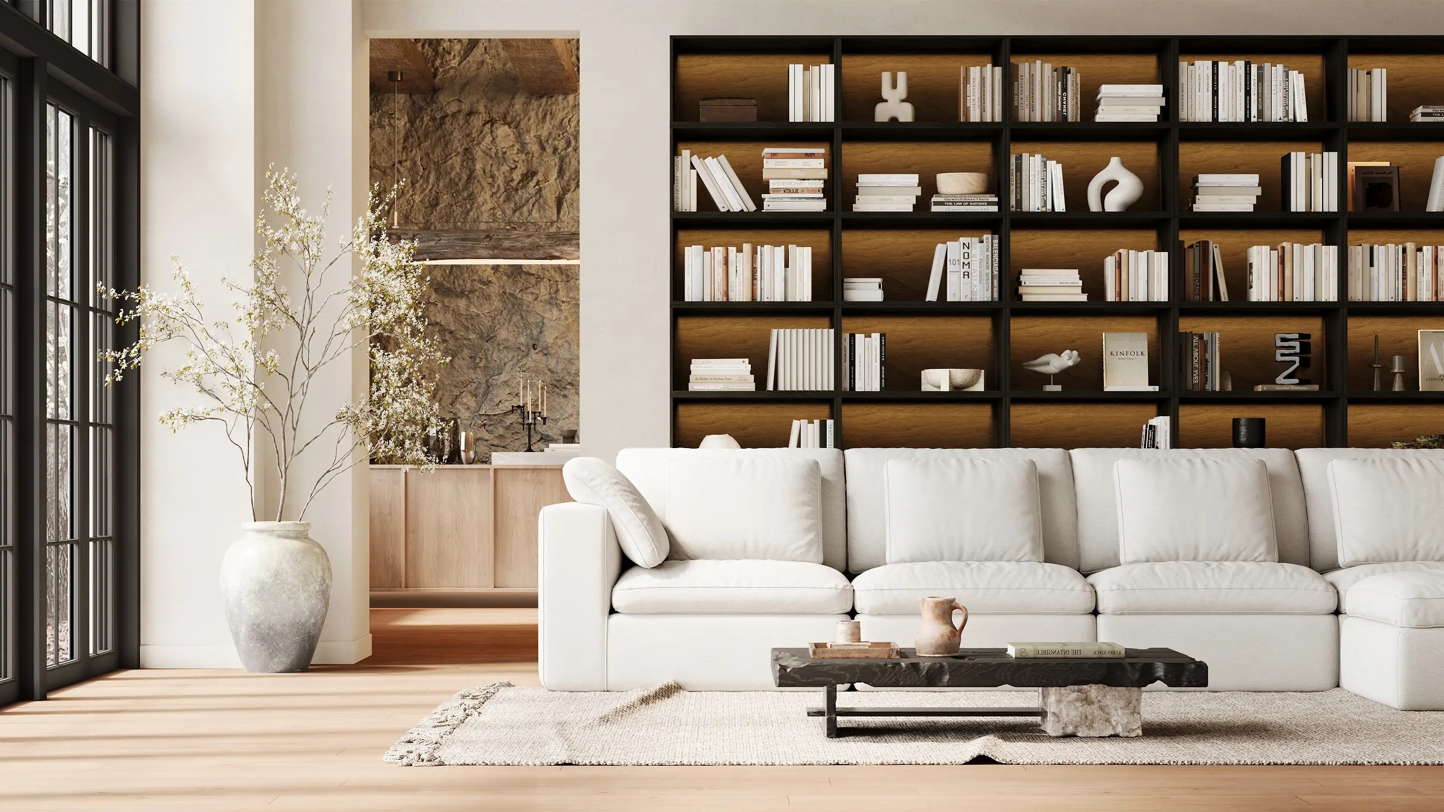 The quiet-style living room is furnished with a modular 4-seater white sofa and a whole wall of modular black bookcases.