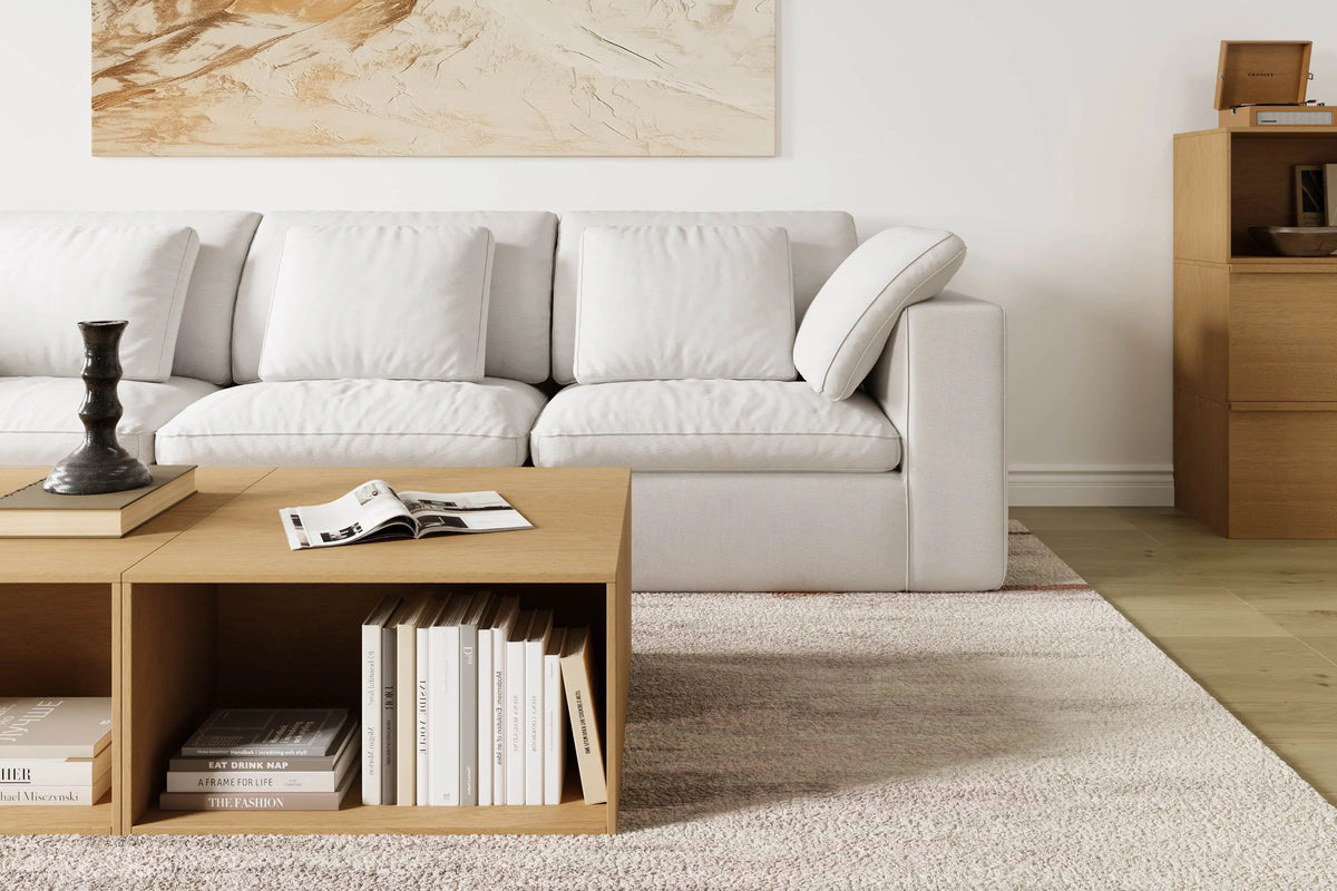 The modern and simple living room is furnished with a modular 4-seater sofa and a modular log-colored coffee table and chest of drawers.